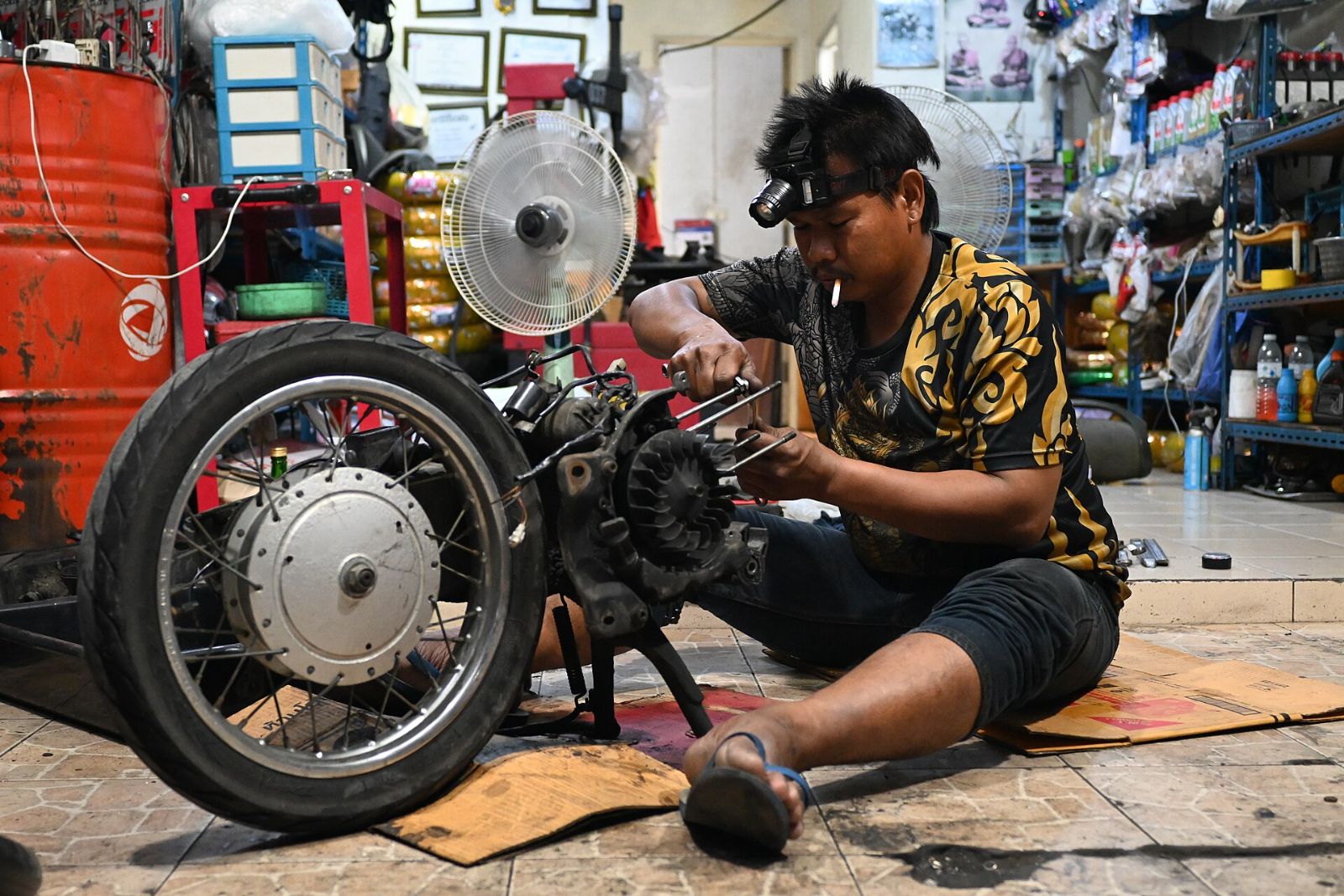 A mechanic working on a motorcycle engine on the workshop floor